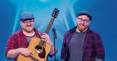 Two men in check shirts playing guitar