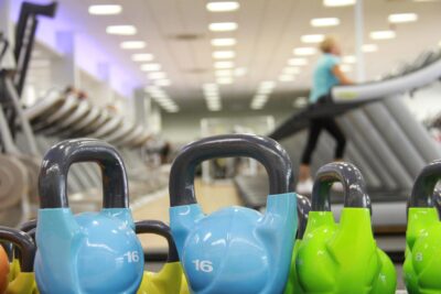 a gym with blue kettlebells in the foreground