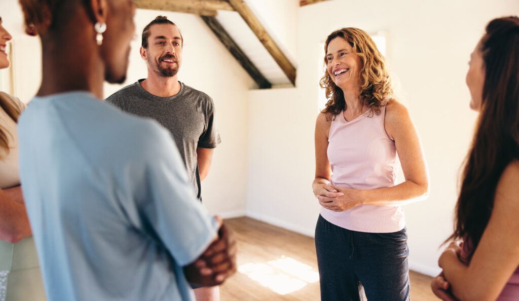 Group,Of,People,Talking,To,A,Yoga,Coach,While,Standing